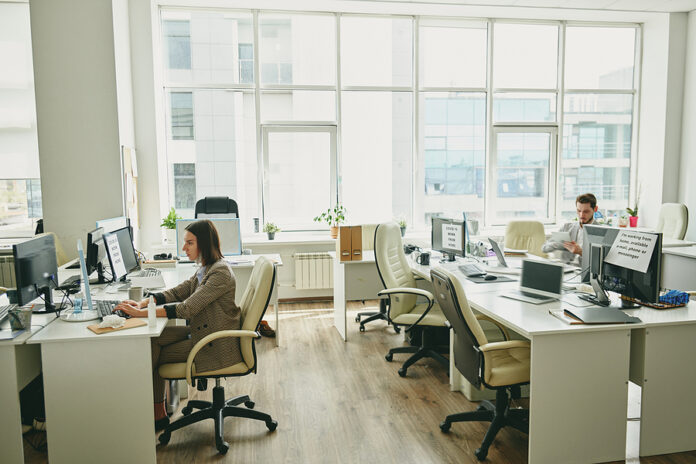 Young people sitting in half-empty office during coronavirus per