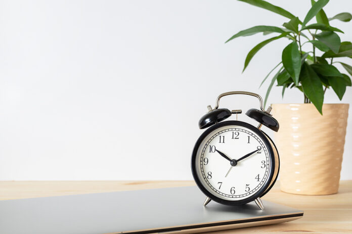 Classic Black Alarm Clock, Laptop And Potted Plant On Wooden Tab