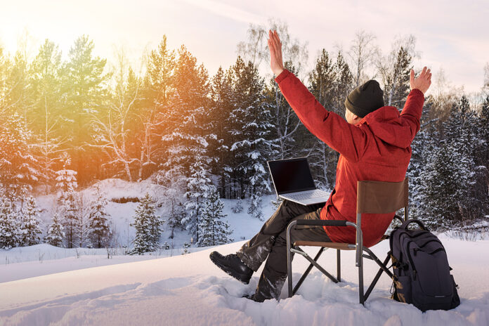 Adult Man Blogger Or Freelancer Working On A Laptop In Winter Fo