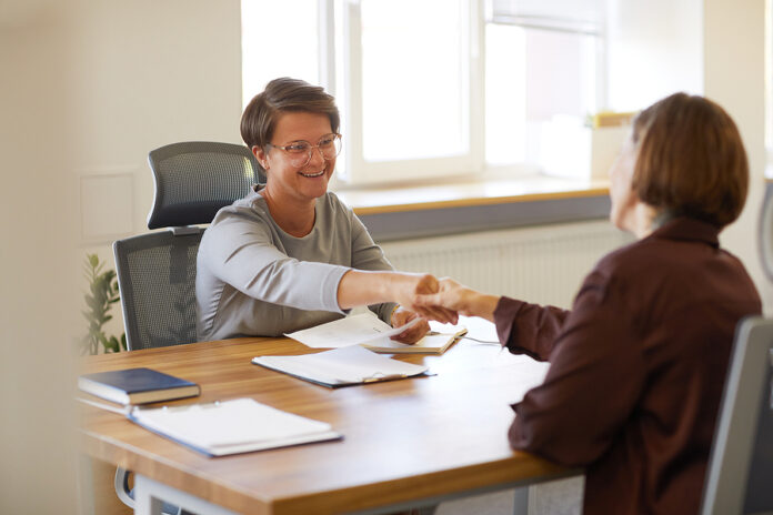 Portrait Of Female Hr Manager Handing Contract To Young Woman At