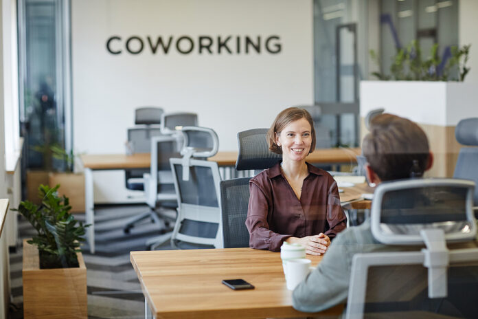 Portrait Of Smiling Young Woman In Job Interview At Office Behin