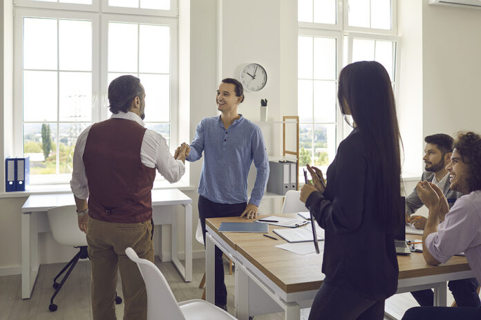 Business Manager Shakes Hands With A Young Cheerful Man, Welcomi