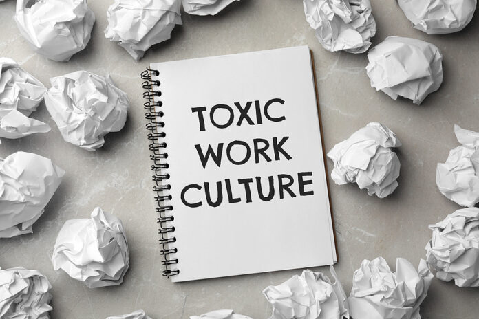 Notebook With Text Toxic Work Culture And Crumpled Paper On Grey