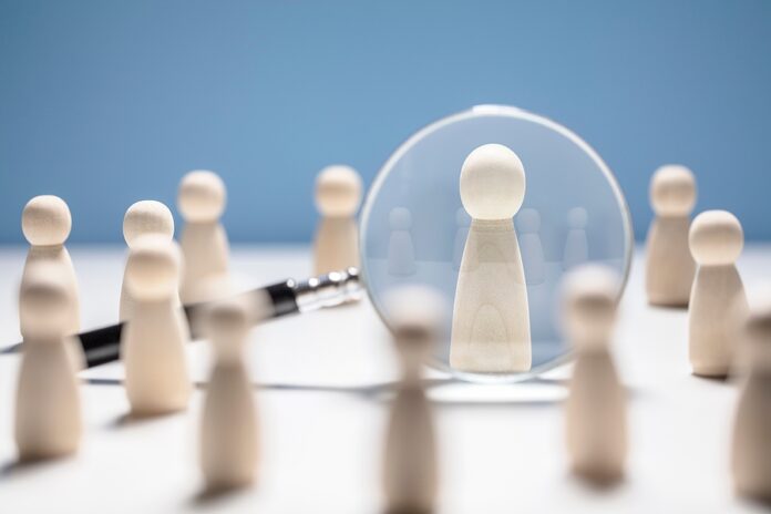 Recruitment and job search magnifying glass with wooden people c
