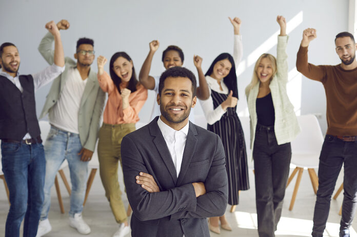 Portrait Of Smiling Black Business Leader With Team Of Happy Emp