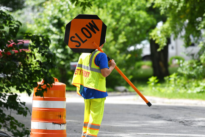 Outdoor Worker Hold Slow Sign At Road Construction Site