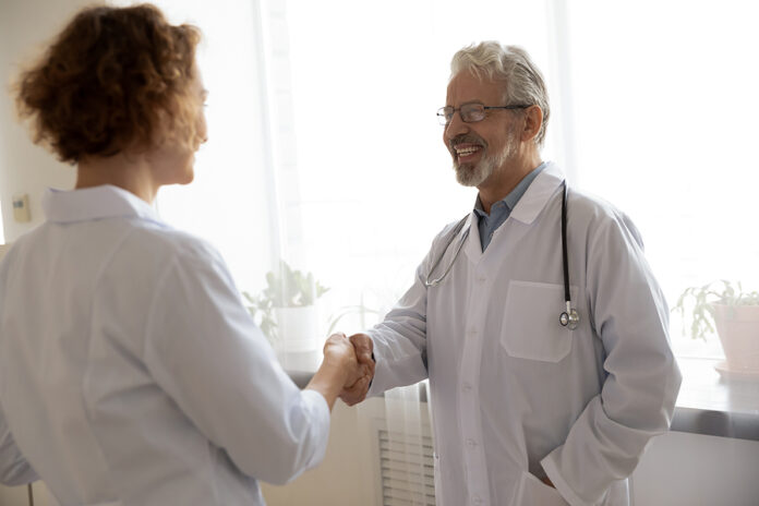 Smiling Mature Doctor Wearing Glasses Greeting Colleague, Shakin