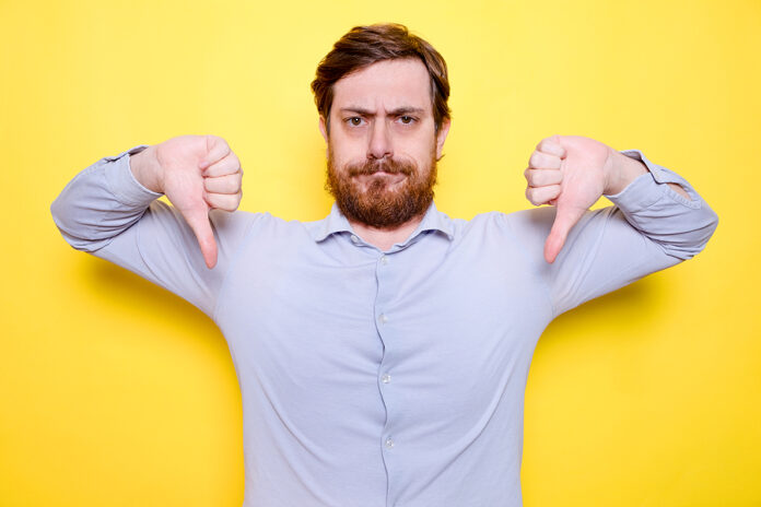 Man Isolated On Yellow Background Showing Thumb Down, Disappoint