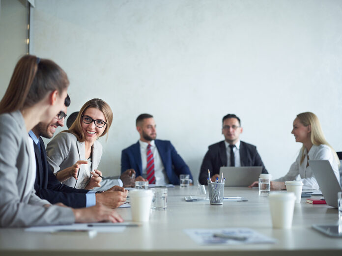 Group of cheerful business people smiling and chatting at meetin