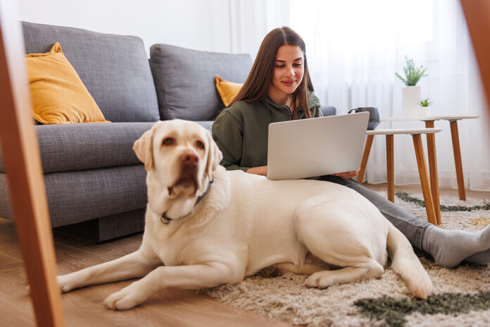 Beautiful Young Woman Cuddling Her Dog While Working Remotely Fr