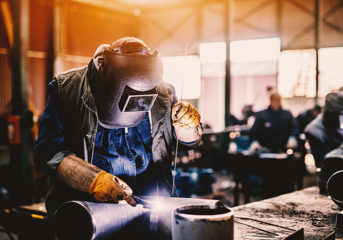 Profesional Welder In Protective Uniform And Mask Welding Metal
