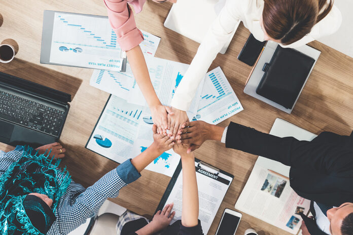 Businessmen And Businesswomen Joining Hands In Group Meeting At
