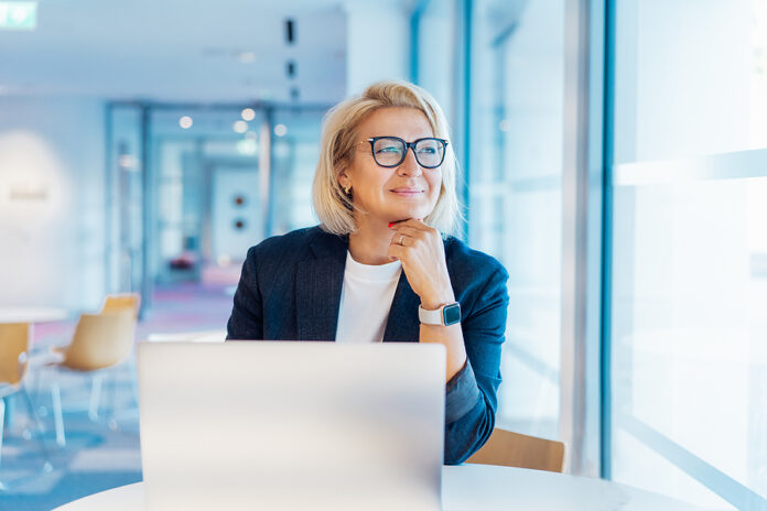 50s Confident Mature Businesswoman Dreamy Looking At Window, Mid
