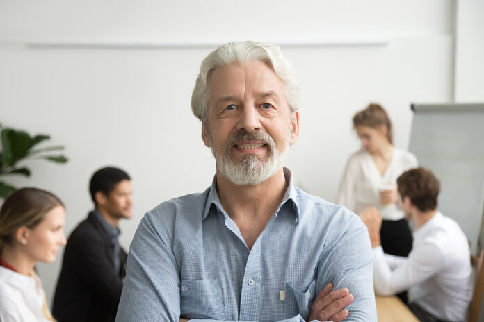 Confident Senior Businessman Leader Looking At Camera With Team