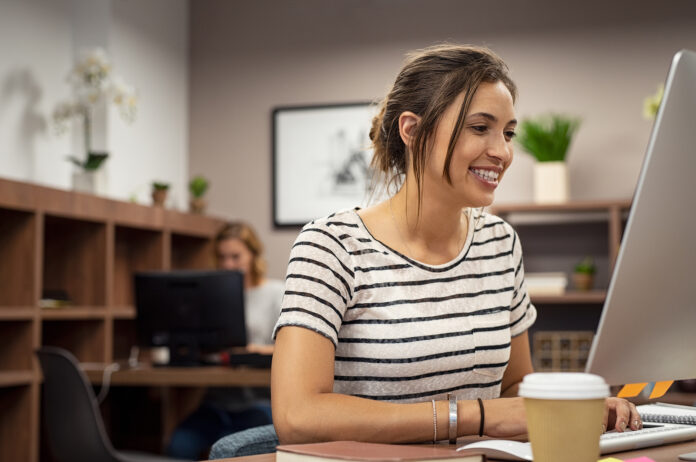 Portrait of smiling young woman working at computer screen. Smil