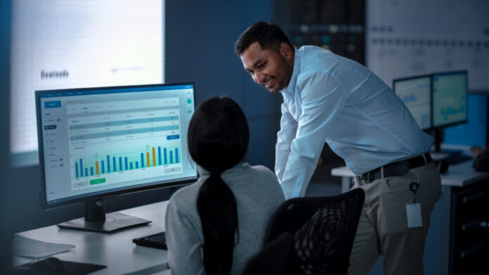 Two Professional Traders Taling and Working in a Modern Monitoring Office with Live Analytics Feed on a Big Digital Screen. Monitoring Room with Brokers and Finance Specialists.
