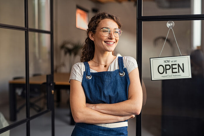 Portrait of happy waitress standing at restaurant entrance. Port