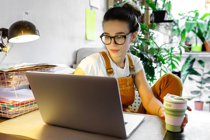 Young Female Gardener In Glasses Using Laptop, Communicates On I