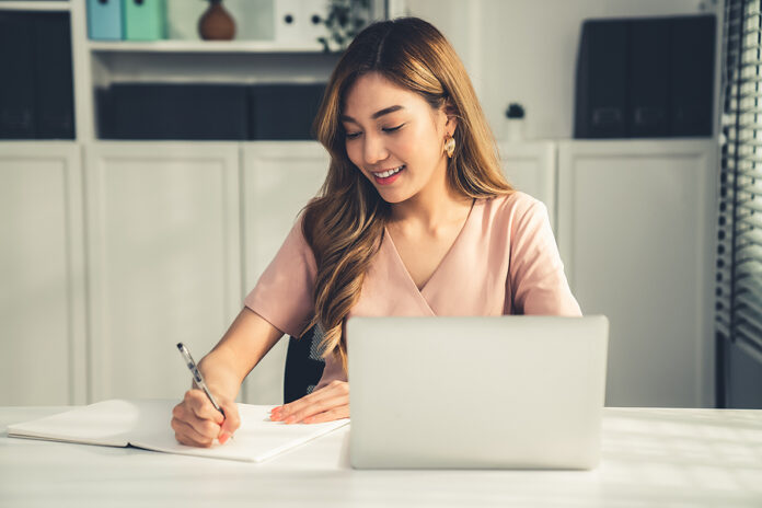 A Young Asian Female Employee Sitting At Her Desk In Her Office,