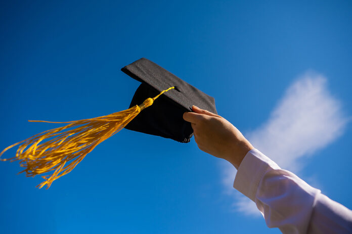 Close-up Of A Womans Hand With A Graduation Cap Against The Blue