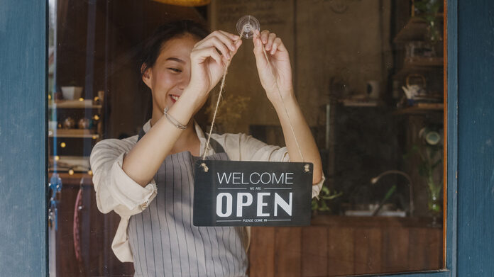 Young Asia Manager Girl Changing A Sign From Closed To Open Sign