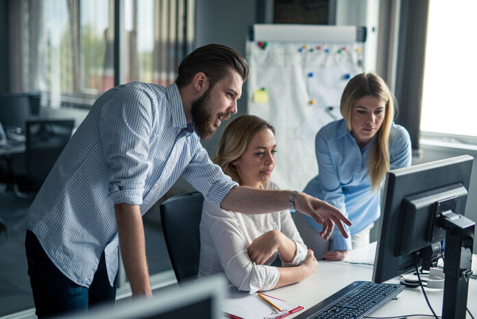 Coworkers looking at a computer and talking about work.