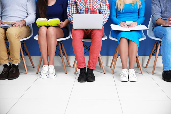 Young people sitting on a chairs in blue hall, close up